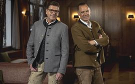 Peter Inselkammer und Heiko Buchta stehen in bayrischer Tracht nebeneinander in der Lobby des Platzl Hotels in München.