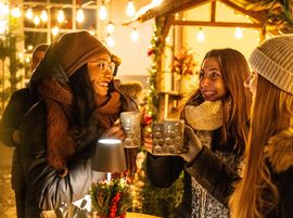Three women toast with mulled wine in the festively decorated Platzl-Hof courtyard.