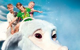 Drei Kinder reiten auf einem weißen Fantasiewesen in der Bavaria Filmstadt in Grünwald.