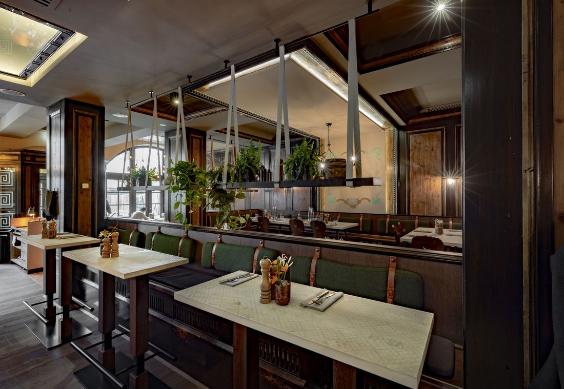 Stilvolles Hotelrestaurant mit Holzakzenten, Polsterbänken und hängender Pflanzendeko