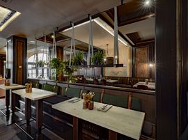 Stilvolles Hotelrestaurant mit Holzakzenten, Polsterbänken und hängender Pflanzendeko