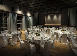 Eingedeckte runde Tische mit weißen Tischdecken im  „Kreszenz – Der Saal“ im Marias Platzl Boutique Hotel München