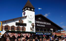 Das Armbrustschützen-Zelt auf dem Oktoberfest hinter traditionellen Essens- und Souvenirständen.