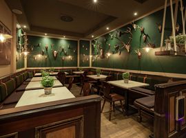 Der Gastraum mit Jagdtrophäen und grüner Wand bietet ein uriges Ambiente zum Verweilen