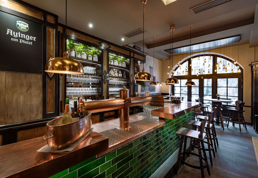 Die Bar im Ayinger am Platzl glänzt mit Kupfertheke, Zapfanlage und stimmungsvollem Licht
