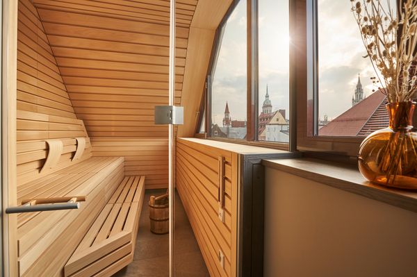 Sauna mit Holzverkleidung und Sitzbänken, großes Fenster mit Blick über die Dächer der Münchner Altstadt.
