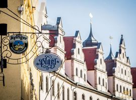 Außenansicht des Platzl Hotels mit Sicht auf die Häuserfront und die Eingangsschilder des Platzl Hotels und des Ayinger am Platzl.