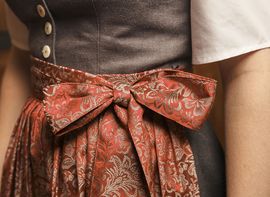 Traditionelles Dirndl mit einer rosa Schürze mit Schleife.