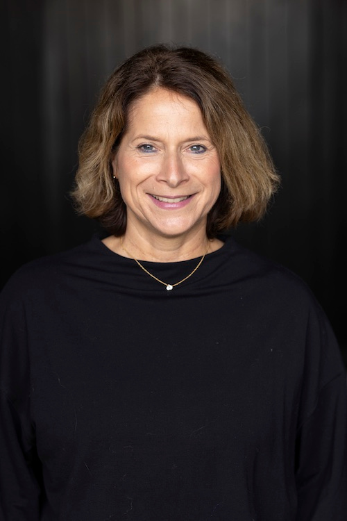 Portrait of a smiling woman with shoulder-length hair against dark backdrop